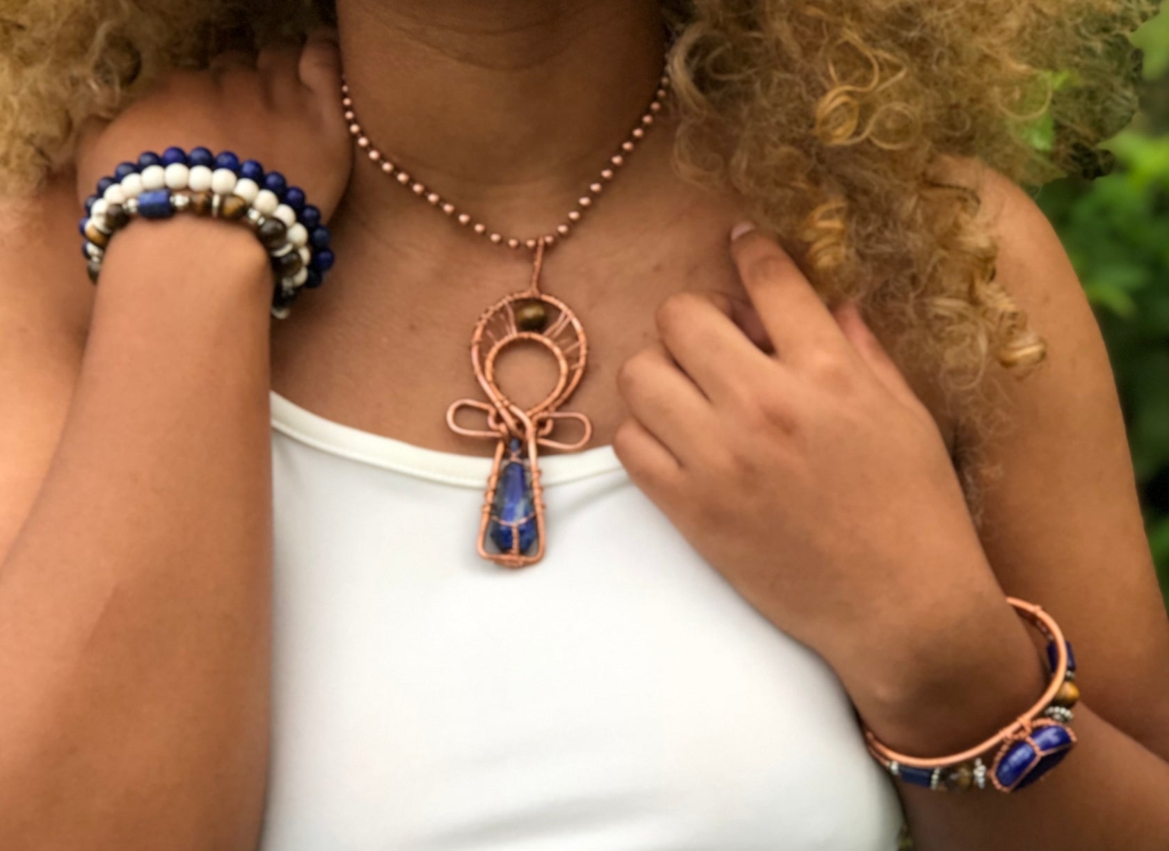 model wearing lapis ankh pendant and howlite, lapis, tigers eye stretchy bracelets. She is also wearing a copper wirewrapped bangle made with lapis lazuli and tigers eye.